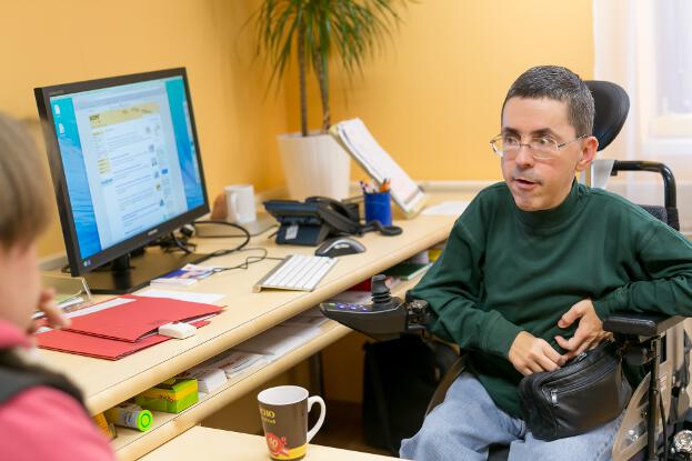 Martin Ladstätter im elektrischen Rollstuhl an seinem Schreibtisch
