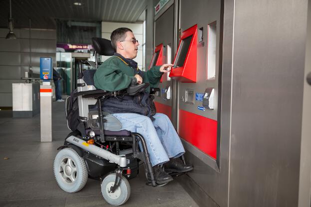 Martin Ladstätter betätigt vom Rollstuhl aus einen Fahrscheinautomaten