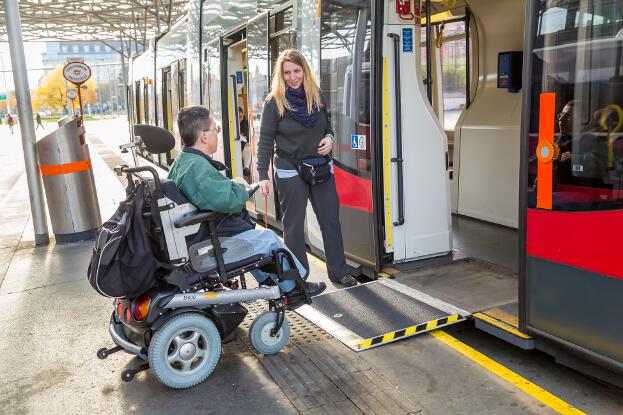 Martin Ladstätter fährt mit seinem Elektrorollstuhl in eine Straßenbahn. Daneben steht die Fahrerin.