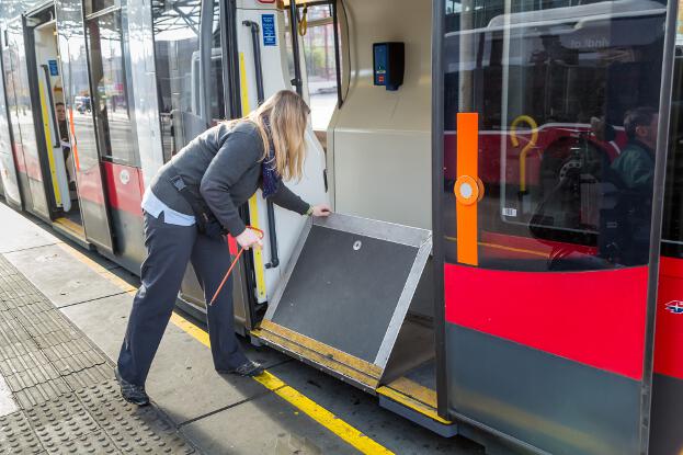 Die Straßenbahnfahrerin klappt die Rampe ein.