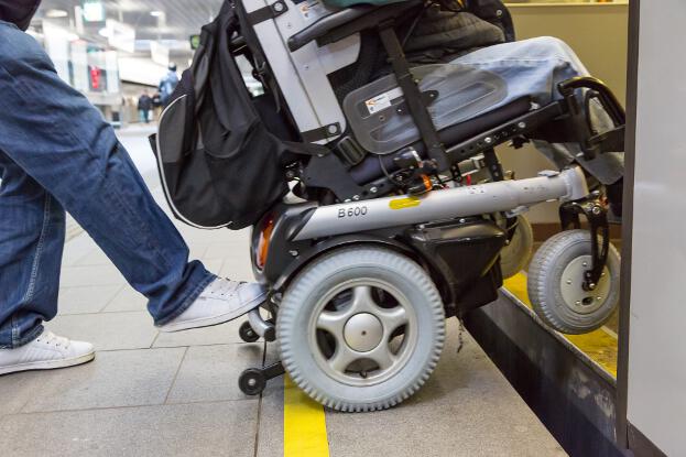 Die Räder des Rollstuhls über dem Spalt zwischen Bahnsteigkante und U-Bahnwagen.