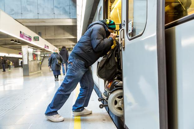 Ein Mann schiebt den Rollstuhl in den U-Bahn-Waggon